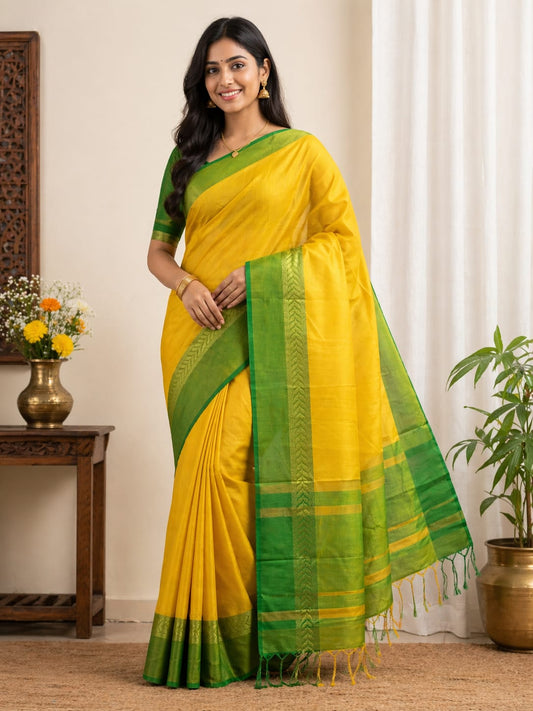 Woman wearing a yellow and green saree in a room with decor elements.
