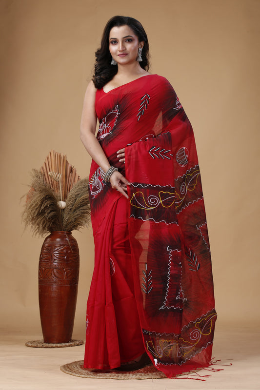 Woman wearing a red saree with intricate patterns on a beige background